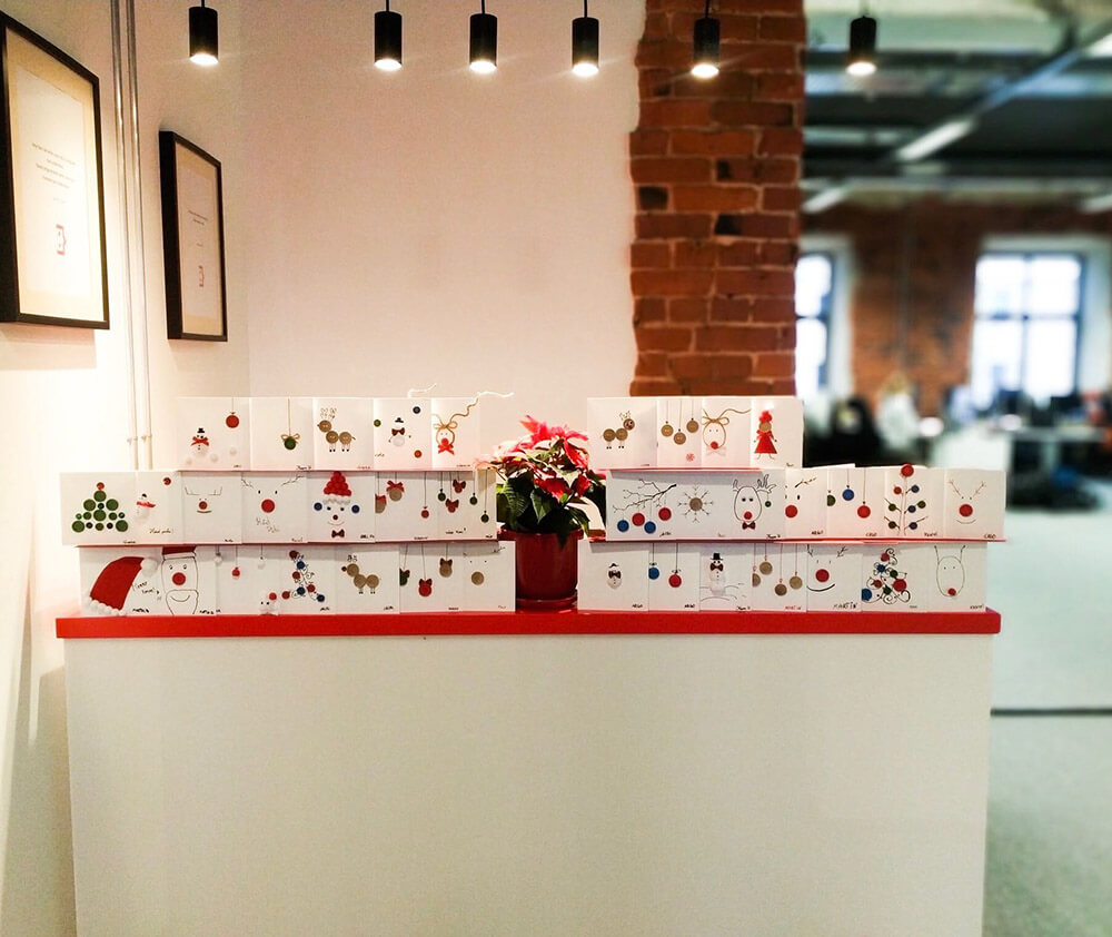 AgileWorksi töötajate valmistatud jõulukaardid laual rivis.